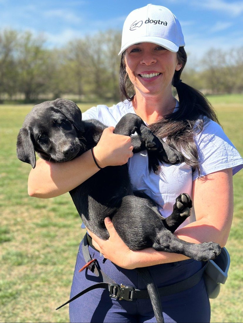 Dog trainer Meg at The Composed Canine holding a labrador puppy during a training session in Austin, TX